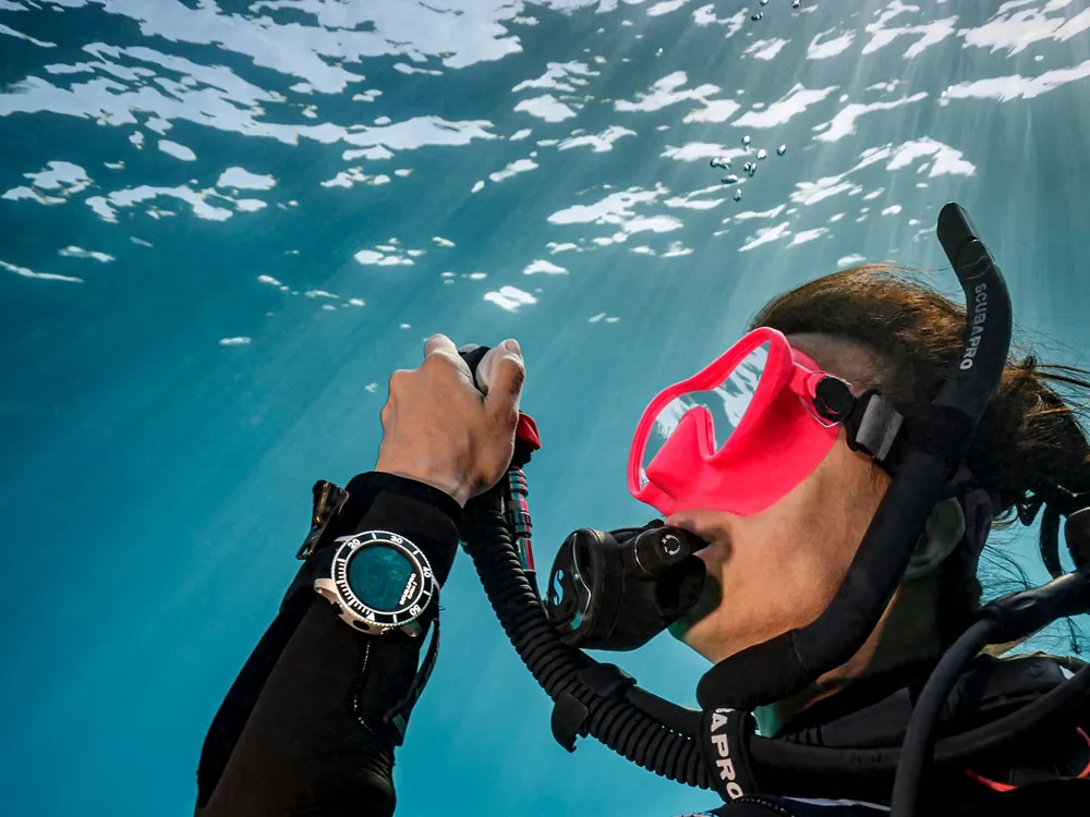 A diver checking a dive computer while holding the inflator
