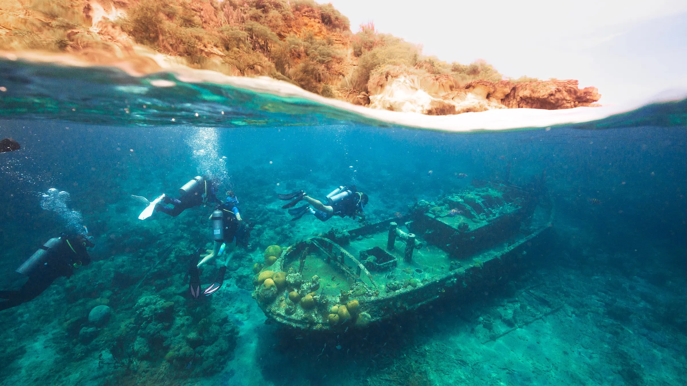 Divers gliding over a wreck just below the surface